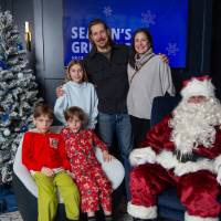 Family with three children smile with Santa